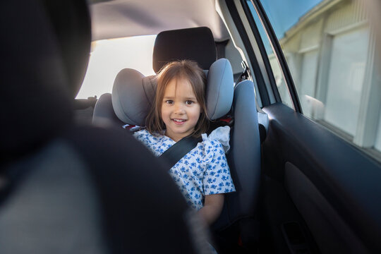 Portrait of smiling girl sitting comfortably in safety seat inside car