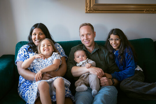 Portrait of multiracial family sitting together on sofa at home