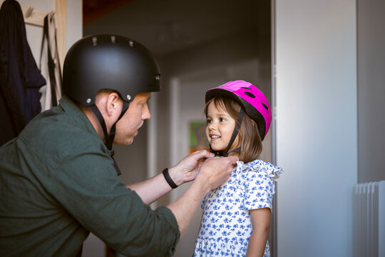Father adjusting his daughter's helmet before outdoor activity