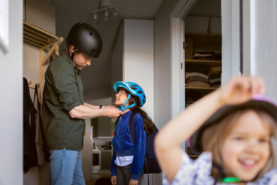 Father putting protective gear on daughter before leaving house