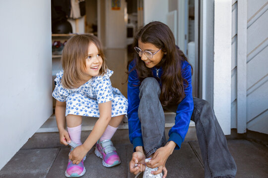 Excited girls tying shoelace before going for outdoor activity