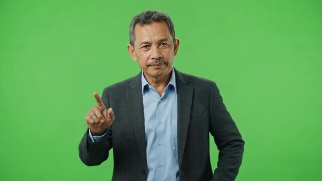 Confident middle-aged man gesturing with finger against a bright green background during a presentation