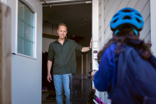 Smiling father saying goodbye to his daughter at front door
