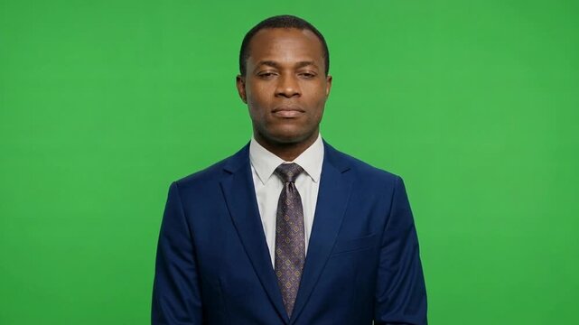 Professional man standing confidently in a blue suit and patterned tie against a green background