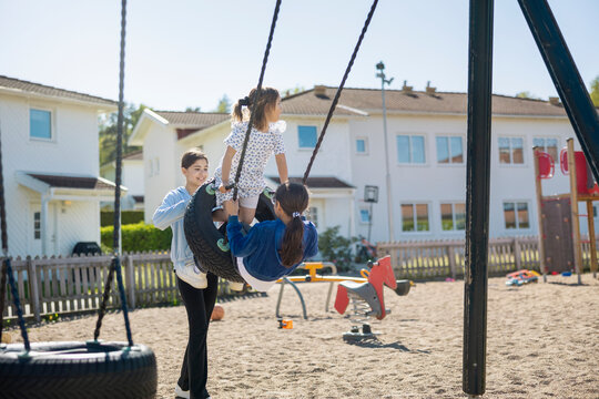 Happy female siblings playing outdoors in sandy playground