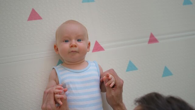 Baby holding father's thumbs with tiny hands. Close-up.