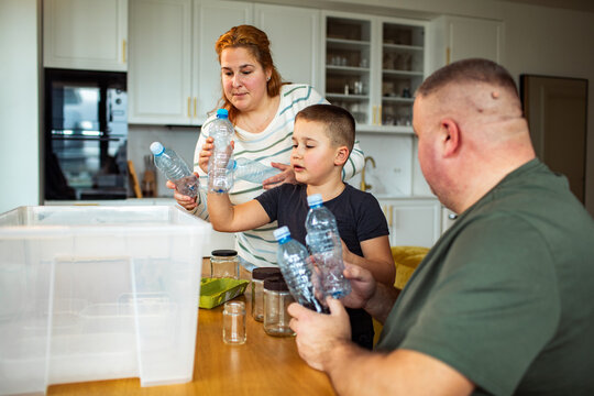 Family sorting plastic bottles for recycling at home kitchen