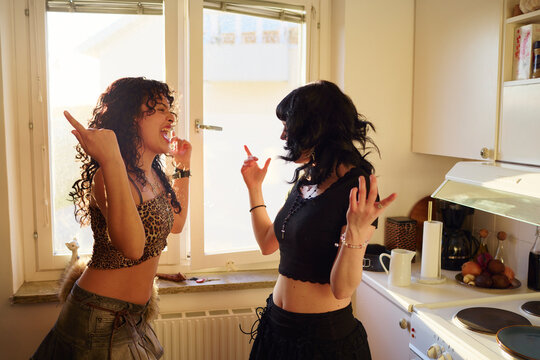 Cheerful lesbian women dancing together in kitchen at home