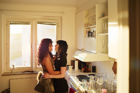 Young lesbian couple sharing intimate moment in their apartment kitchen