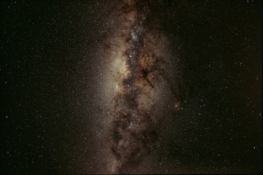 Milky way galaxy band across a dark night sky, revealing a dense concentration of stars, interstellar gas, and dark dust lanes within the galactic center