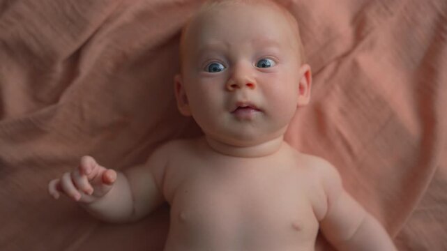 Baby moving arms and legs on cloth and sneezing. Close-up.