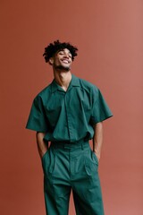 Obraz premium Standing full body young man in coordinated green outfit on terracotta backdrop for vertical poster and editorial fashion background