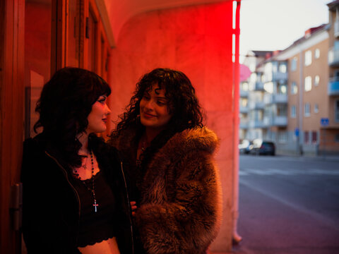 Romantic lesbian couple looking at each other while standing next to door