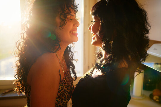 Happy lesbian woman spending quality time with her girlfriend in sunlit kitchen