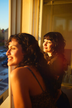 Young lesbian couple looking out of window during sunset