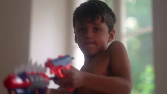 Young boy pointing colorful toy blasters during imaginative indoor play session capturing pretend action, childhood creativity and carefree family home entertainment