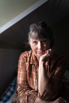 Portrait of mature woman leaning on elbow while sitting in bedroom at home