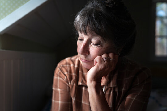 Mature woman leaning on elbow with eyes closed at home