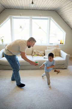 Full length of happy father and son playing with toys in living room at home