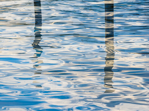 Close-up shot of lake water surface with reflection of pole