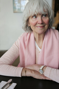 Smiling senior woman looking away while sitting at dining table in home