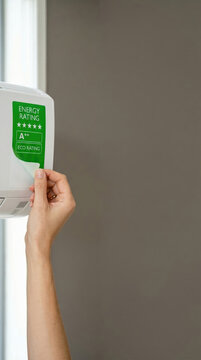 Woman technician installing energy efficiency label on air conditioner. Professional maintenance and climate control system upgrade. Sustainability and environmental saving concept.