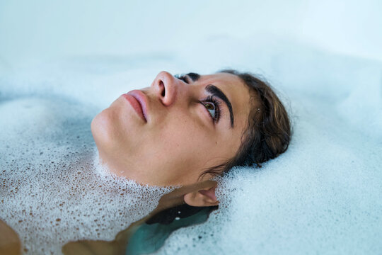A white woman relaxes in a soothing bubble bath