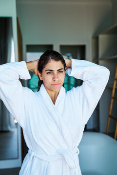 A woman in a white bathrobe standing indoors in a bathroom