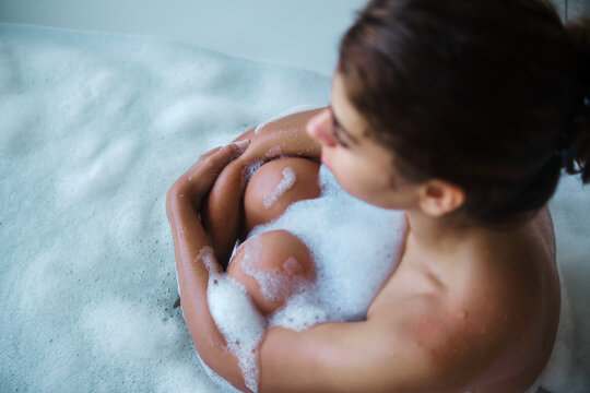 A white woman relaxing with a bubble bath in a bathtub