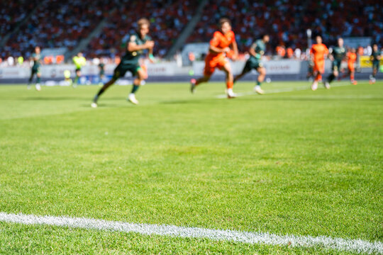 Professional soccer field with green grass and blurred stadium crowd under bright floodlights, creating a dynamic background for football and sports concepts.