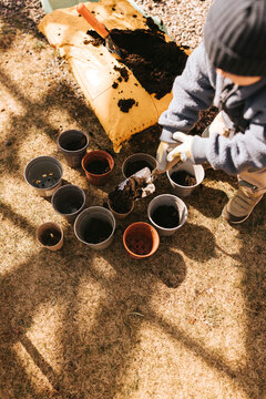 High angle view of boy pouring soil in pots while standing in back yard garden