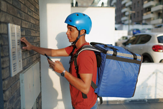 Delivery man rings bell at destination while checking his phone app for instructions