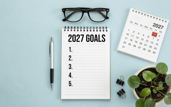 2027 goals notebook with calendar, glasses, and pen on light blue background