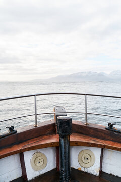 View from the bow of a wooden boat overlooking the ocean and mountains