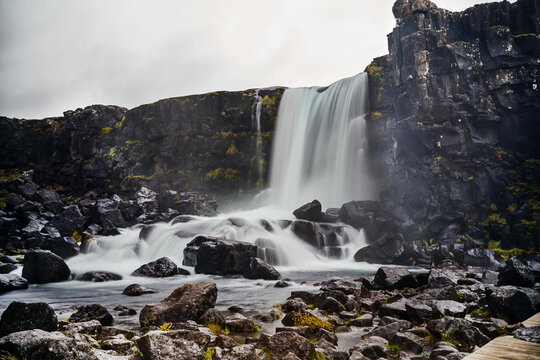 Waterfall flowing over rocky cliff in a natural landscape