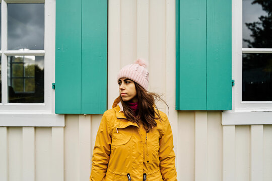 White Woman standing outdoors wearing yellow jacket and pink knit hat