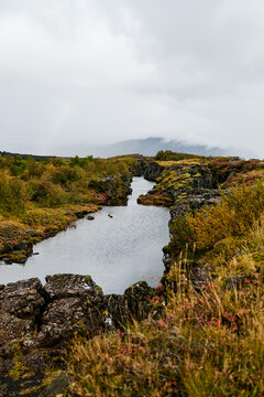 A river flows through mossy rocky terrain with autumn foliage