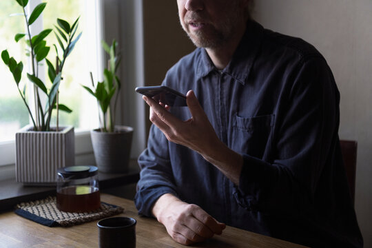 Midsection of senior man talking on speaker phone while sitting at home