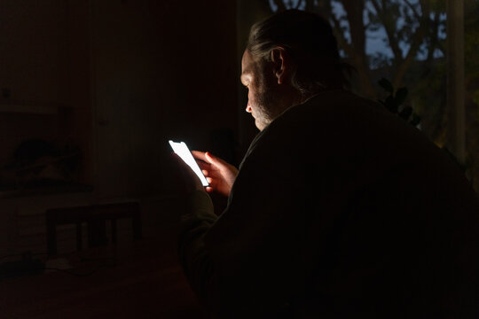 Senior man using smart phone during late night in dark room