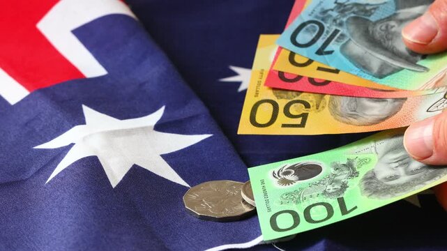 Australian Dollar banknotes on Australia national flag background. Domestic financial market analysis, federal budget, international trade and scannable economy concept.