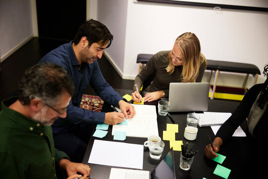 High angle view of male and female coworkers brainstorming during office workshop