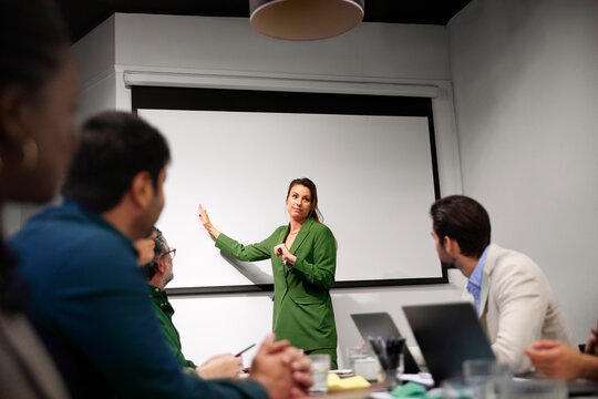 Businesswoman pointing at projection screen during presentation in meeting room