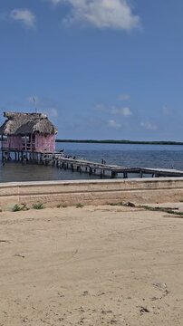 Scenic tropical lagoon surrounded by mangrove forest in Rio Lagartos, Yucatan, Mexico, with traditional thatched palapas and wooden pier under a dramatic cloudy blue sky. Peaceful ecotourism destinati