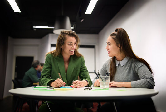 Smiling female business professionals discussing during brainstorming session at office