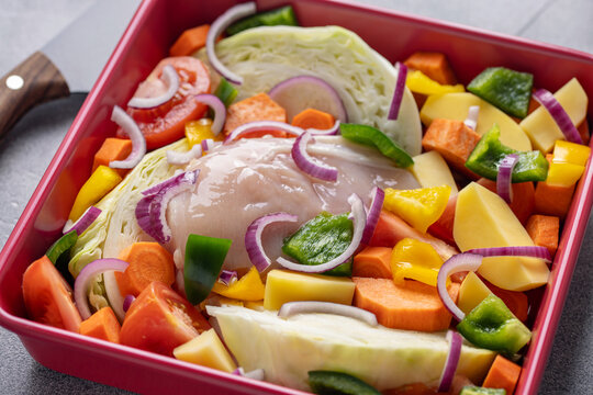 Raw chicken breast and vegetables in a cast iron pan.