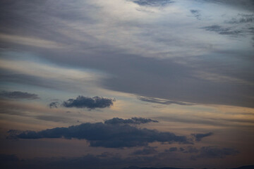 Clouds drift across a twilight sky during sunset, creating a serene and moody atmosphere. © Sumith