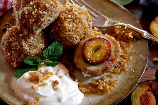 Homemade sweet plum dumplings with breadcrumbs, walnut and cinnamon on a wooden background