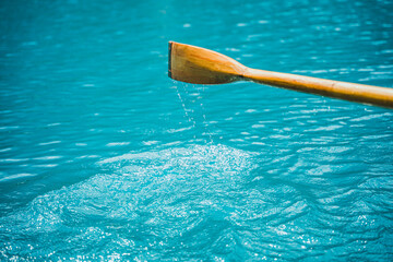 Close-up of a wooden boat paddle over clear turquoise water at Lago di Braies in the Italian Dolomites, capturing an alpine boating and travel experience. © Anastasia
