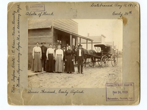 Vintage archival photograph of a historical family group and horse-drawn carriage in front of a rustic wooden building from the early twentieth century