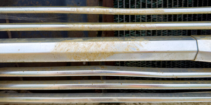 Close-up of old chrome grill on a dilapidated car with rust and dirt
